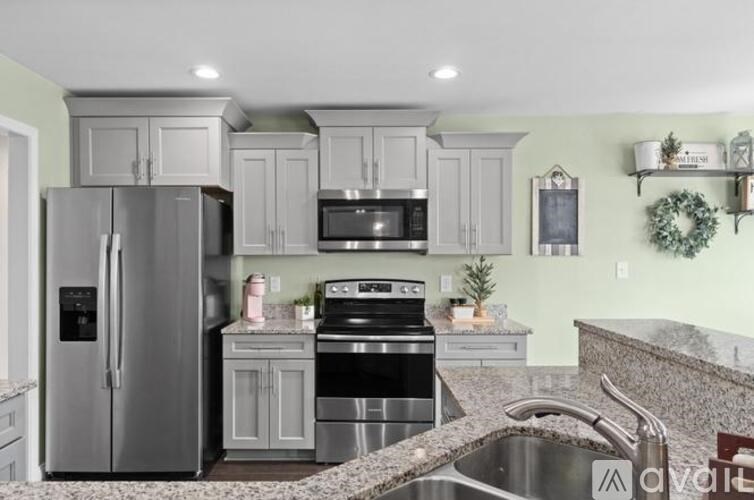 A kitchen with a stainless steel refrigerator and a black stove top oven.