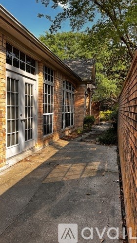 A brick building with a white door and windows is surrounded by a brick wall.
