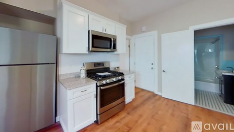 A kitchen with white cabinets and a stainless steel refrigerator.