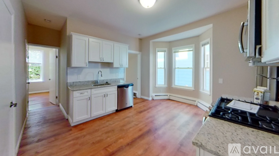 A kitchen with white cabinets and a wooden floor.