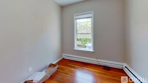 A room with a window and wooden flooring.