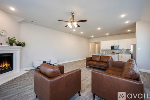 A living room with brown leather chairs and a fireplace.