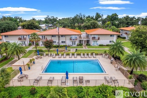 A pool surrounded by lounge chairs and umbrellas is the centerpiece of a resort-style outdoor area.