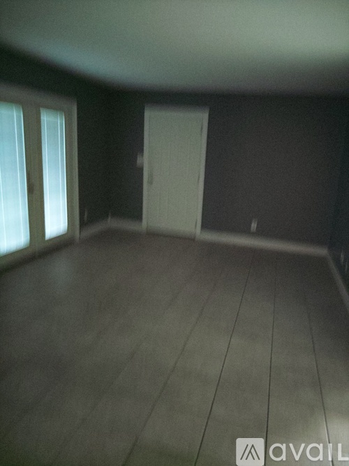 A room with a white door and a window with white blinds.