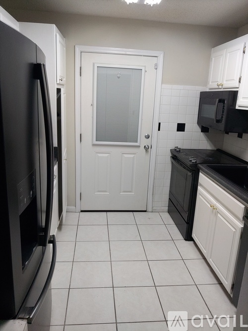 A kitchen with black appliances and white cabinets.