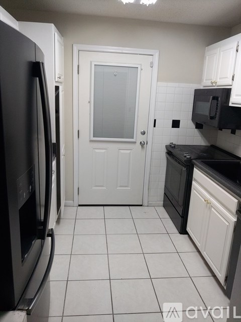 A kitchen with black appliances and white cabinets.