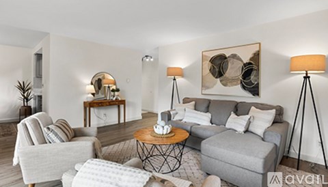 A living room with a grey couch, a coffee table, and a painting on the wall.