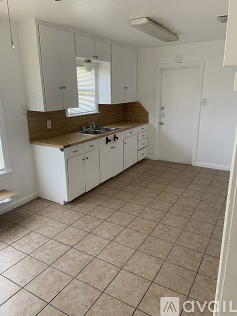 A kitchen with white cabinets and a brown countertop.