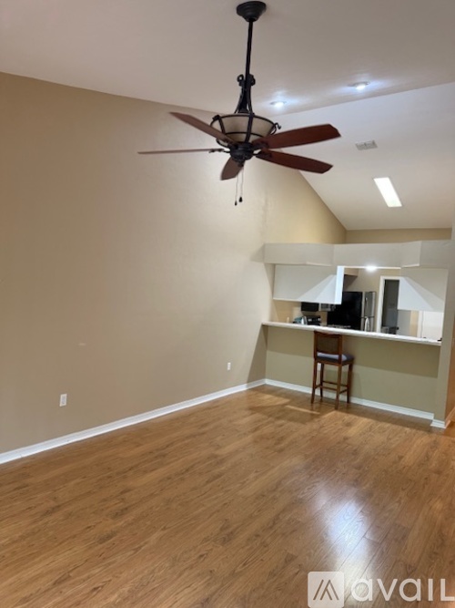 A room with a ceiling fan and wooden flooring.