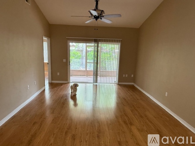 A dog is standing in a room with wooden floors and a ceiling fan.