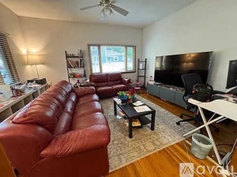 A living room with a red leather couch and a television.