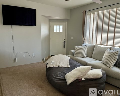 A living room with a bean bag chair and a flat screen TV mounted on the wall.