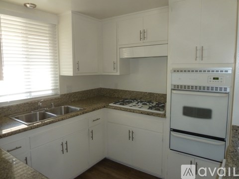 A kitchen with white cabinets and a granite countertop.