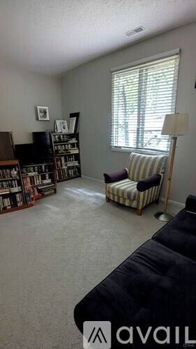 A living room with a black couch and a bookshelf filled with books.