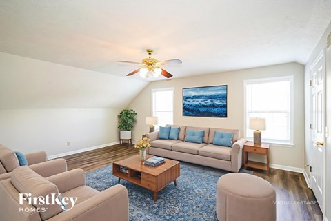 A living room with a blue rug and a painting on the wall.