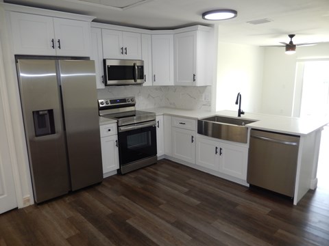 A kitchen with white cabinets and a wooden floor.