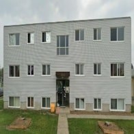 A grey building with a black door and windows.