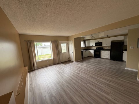 A spacious living room with a kitchen in the background.