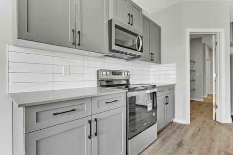 A modern kitchen with a stove top oven and microwave above it.