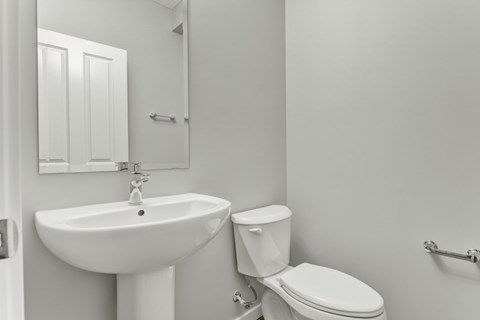 A white bathroom with a toilet, sink, and towel rack.