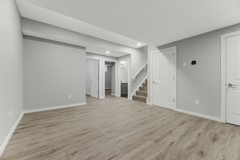 A spacious room with wooden flooring and white walls.