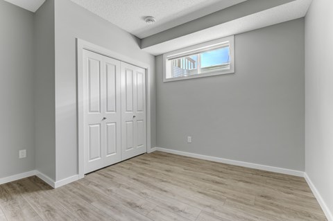 A room with a white door and a window with a view of a building outside.