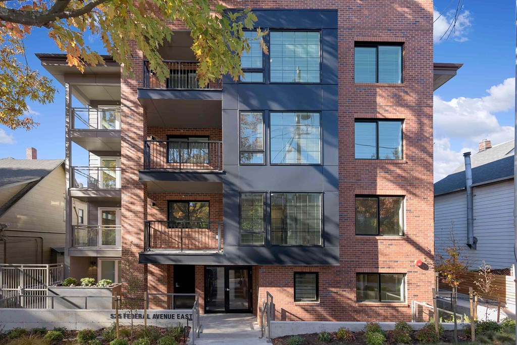 A modern brick building with balconies and large windows.