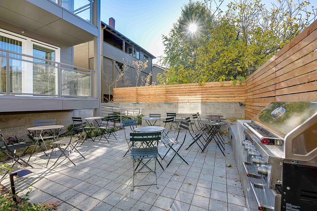 A patio with a grill and chairs.