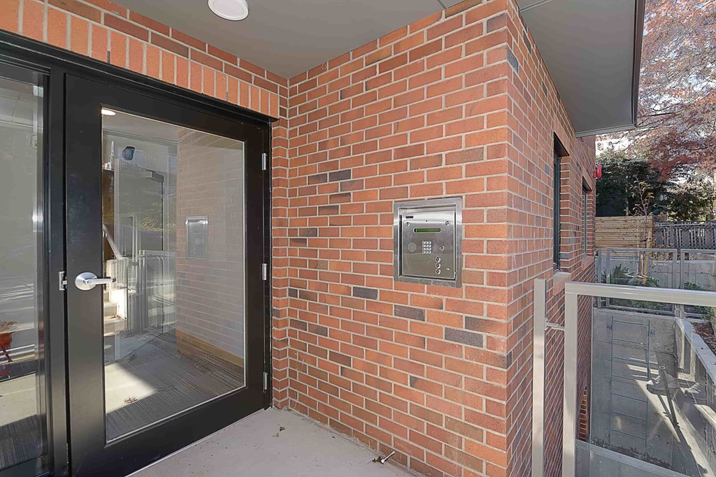 A brick wall with a black door and a small window.