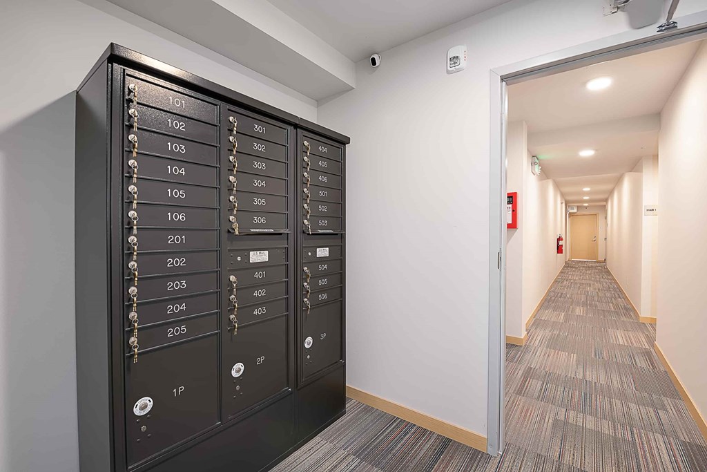 A long hallway with a black panel on the wall with numbers and switches.