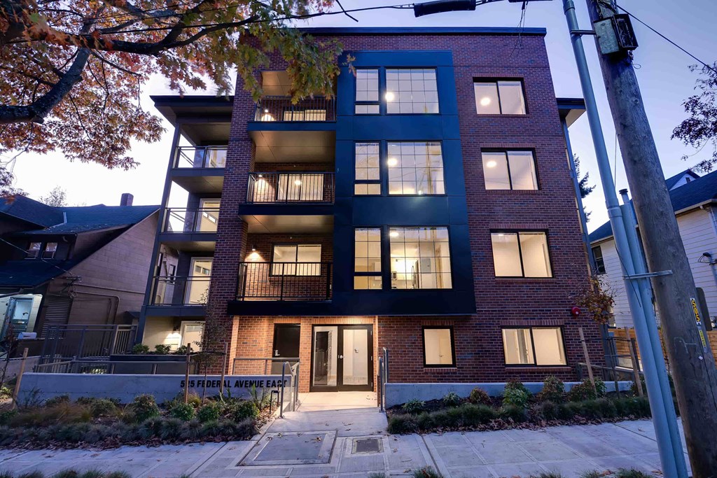 A modern apartment building with a dark blue facade and a black door.
