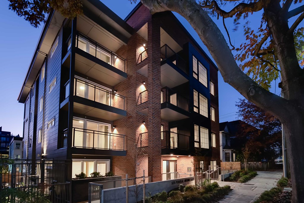 A modern apartment building with a tree in the foreground.