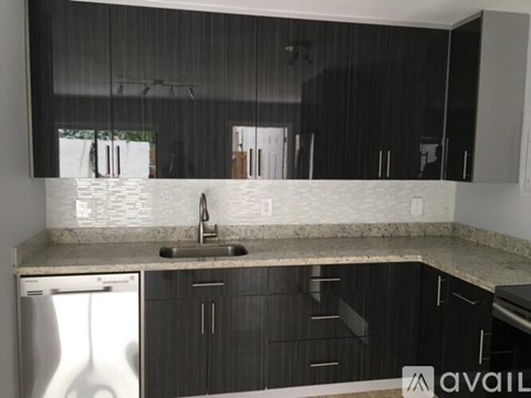 A kitchen with black cabinets and a white dishwasher.