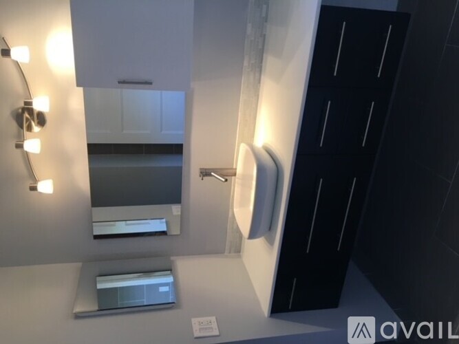 A bathroom with a sink, mirror, and lighting fixtures.