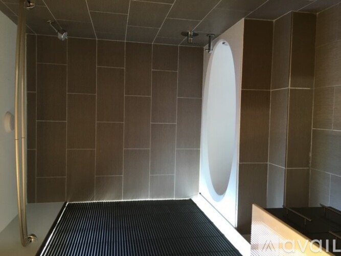 A modern bathroom with a walk-in shower and a black floor mat.
