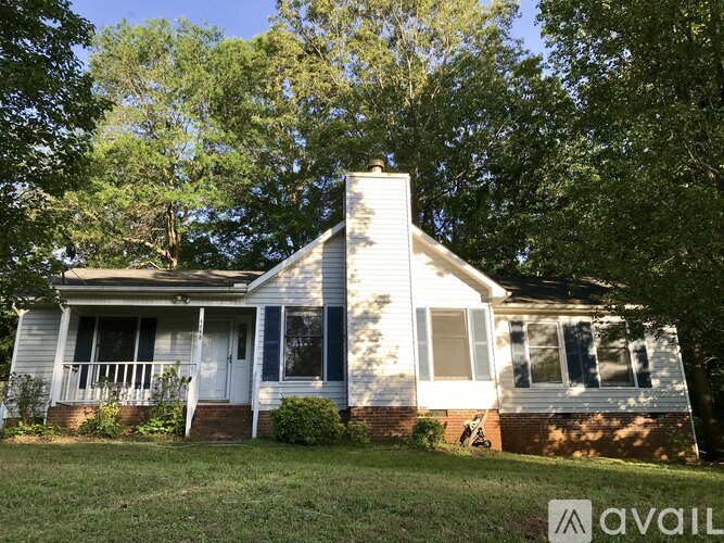A house with a chimney and a porch is surrounded by trees.