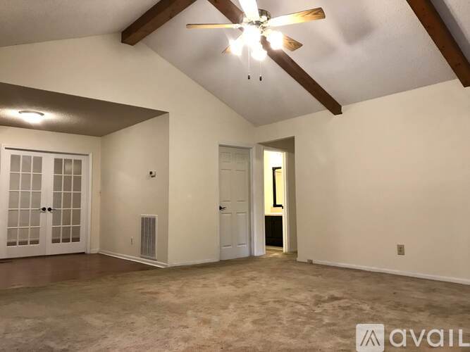 A spacious room with a ceiling fan and a door leading to another room.