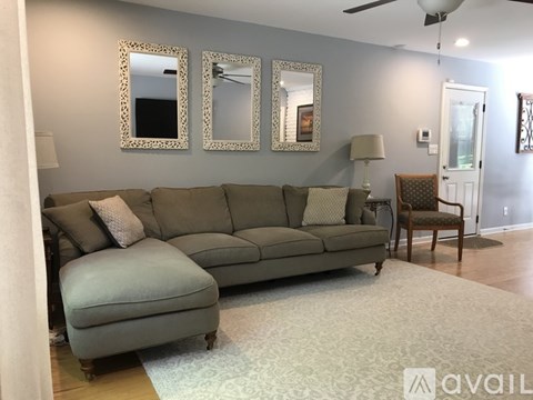 A living room with a grey sofa and two mirrors on the wall.