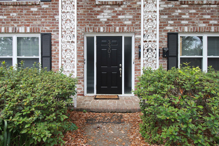 A black door is flanked by two windows with white trim.