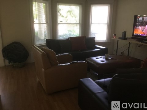 A living room with a couch, chair, ottoman, and television.