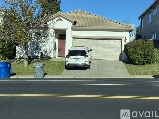 A white car is parked in front of a house.