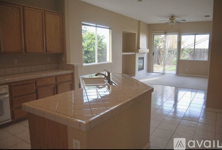 A kitchen with a tile counter top and wooden cabinets.
