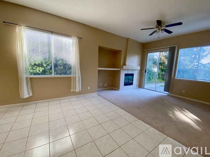 A spacious living room with a ceiling fan and sliding glass doors.