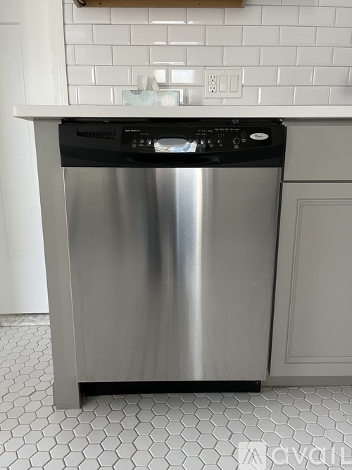 A stainless steel dishwasher in a kitchen with white tiles.
