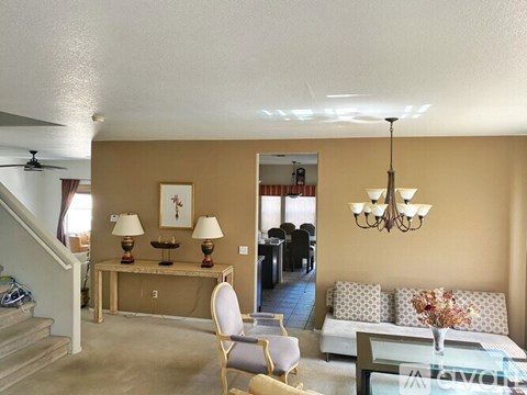 A living room with a couch, chairs, and a table with lamps.