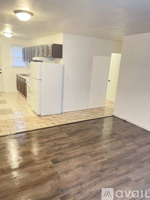 A kitchen with white appliances and wooden floors.