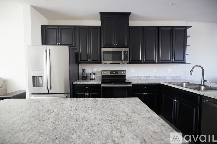 A kitchen with black cabinets and a white refrigerator.