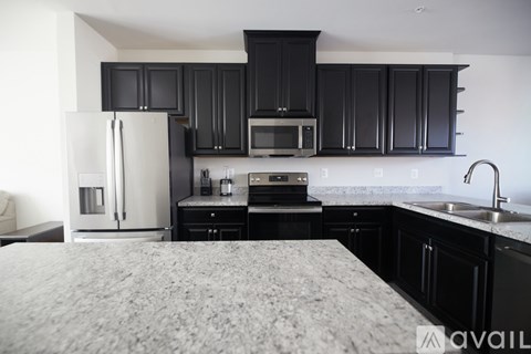 A kitchen with black cabinets and a white refrigerator.