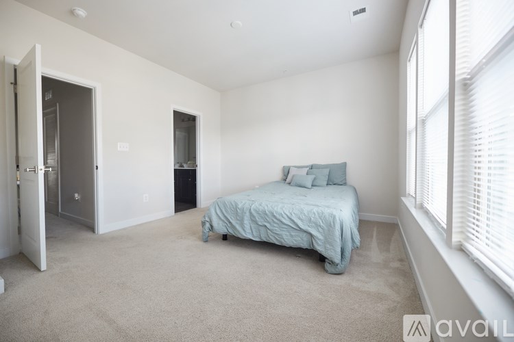 A bedroom with a bed and a window with blinds.