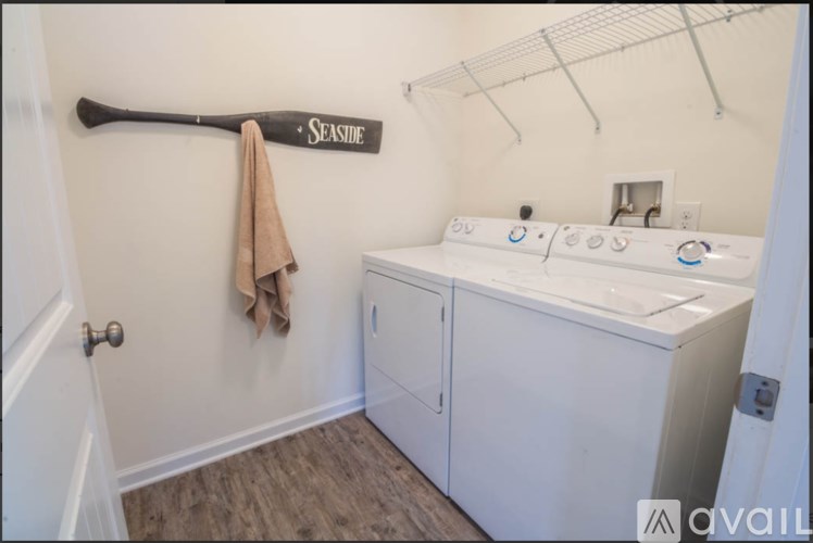 A white double sink bathroom with a wooden floor and a white washer and dryer.